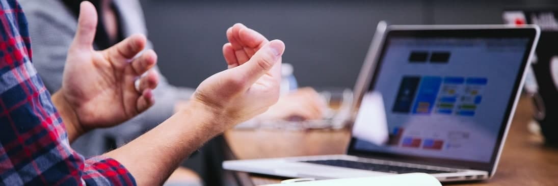 Personas conversando alrededor de una mesa de reunión con una notebook abierta